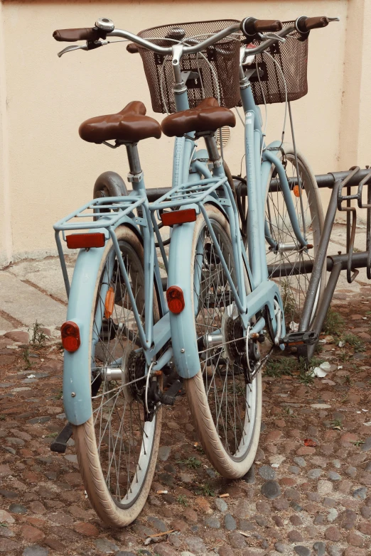 two blue bikes parked together against a building