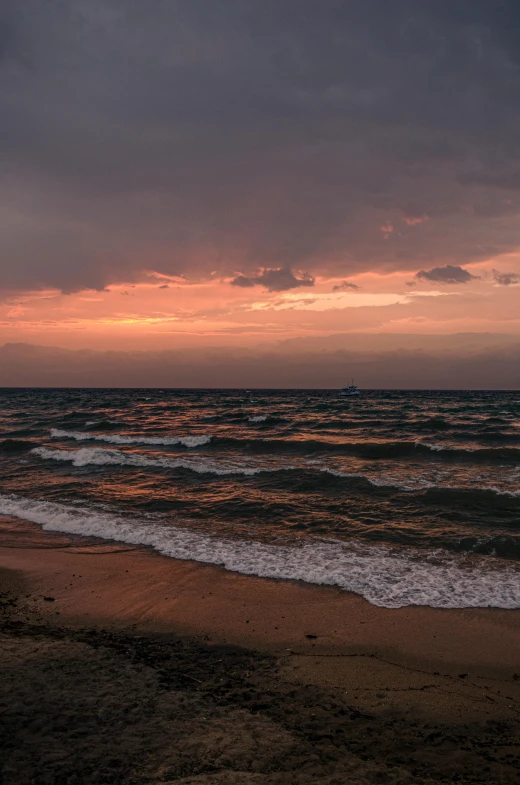 a sunset view of the ocean and waves from the beach