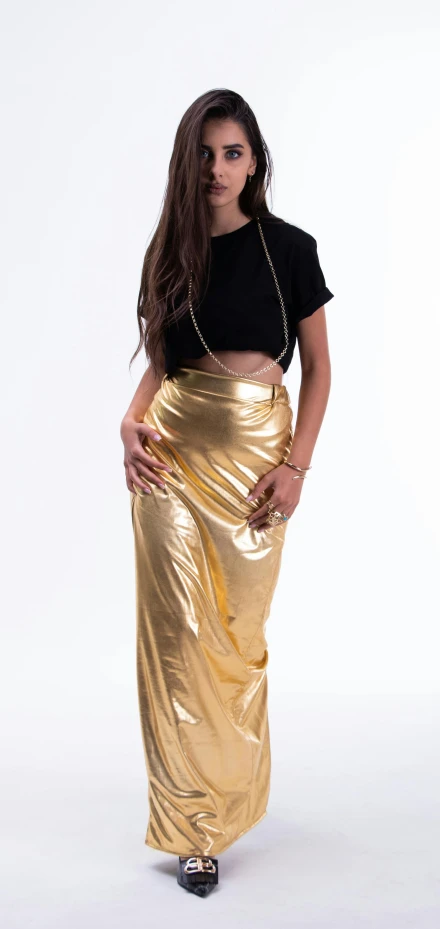 the woman is posing in a shiny gold skirt