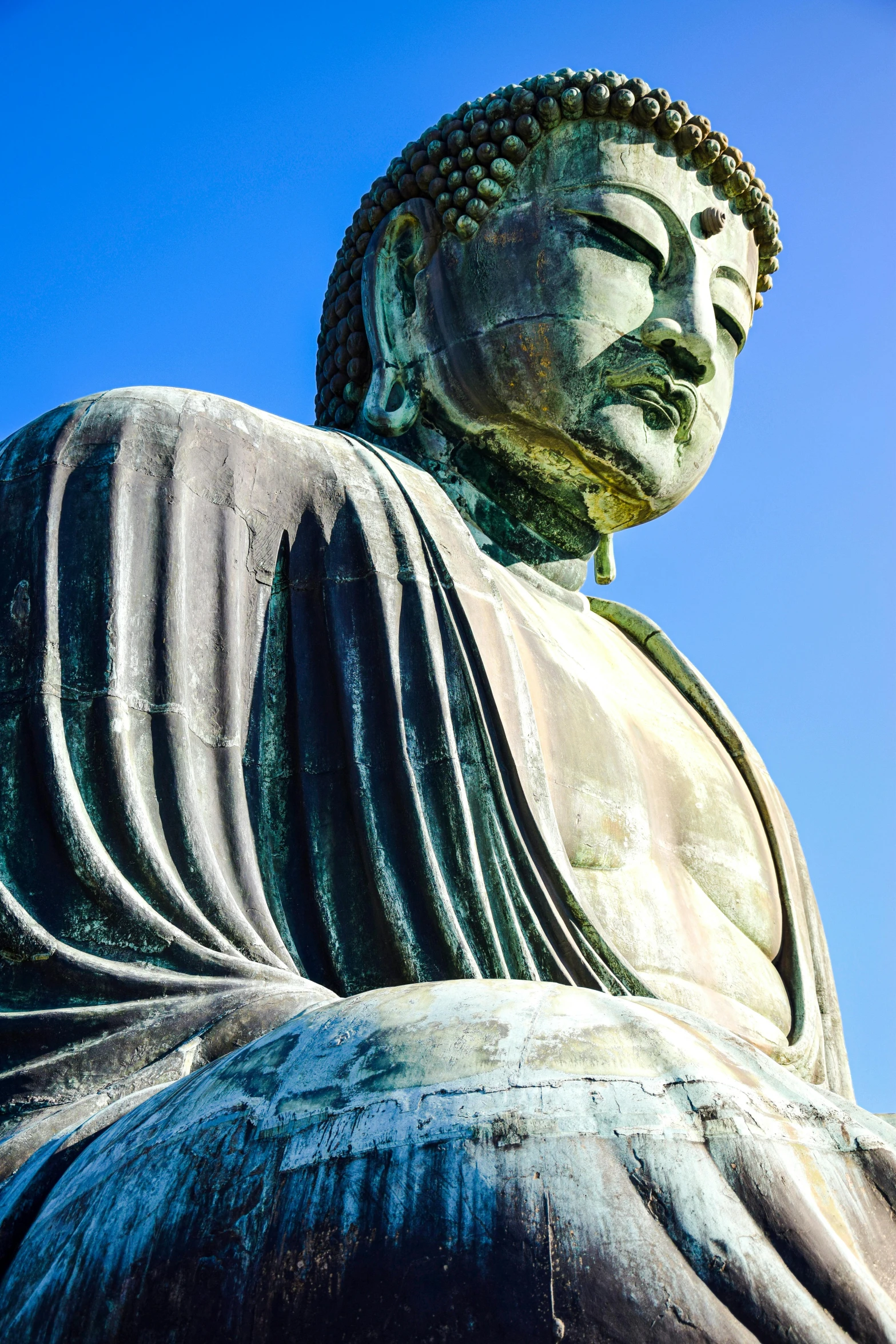 the big buddha statue is posed against a blue sky
