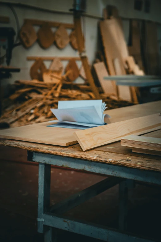 a table in a wood shop with some sheets of paper