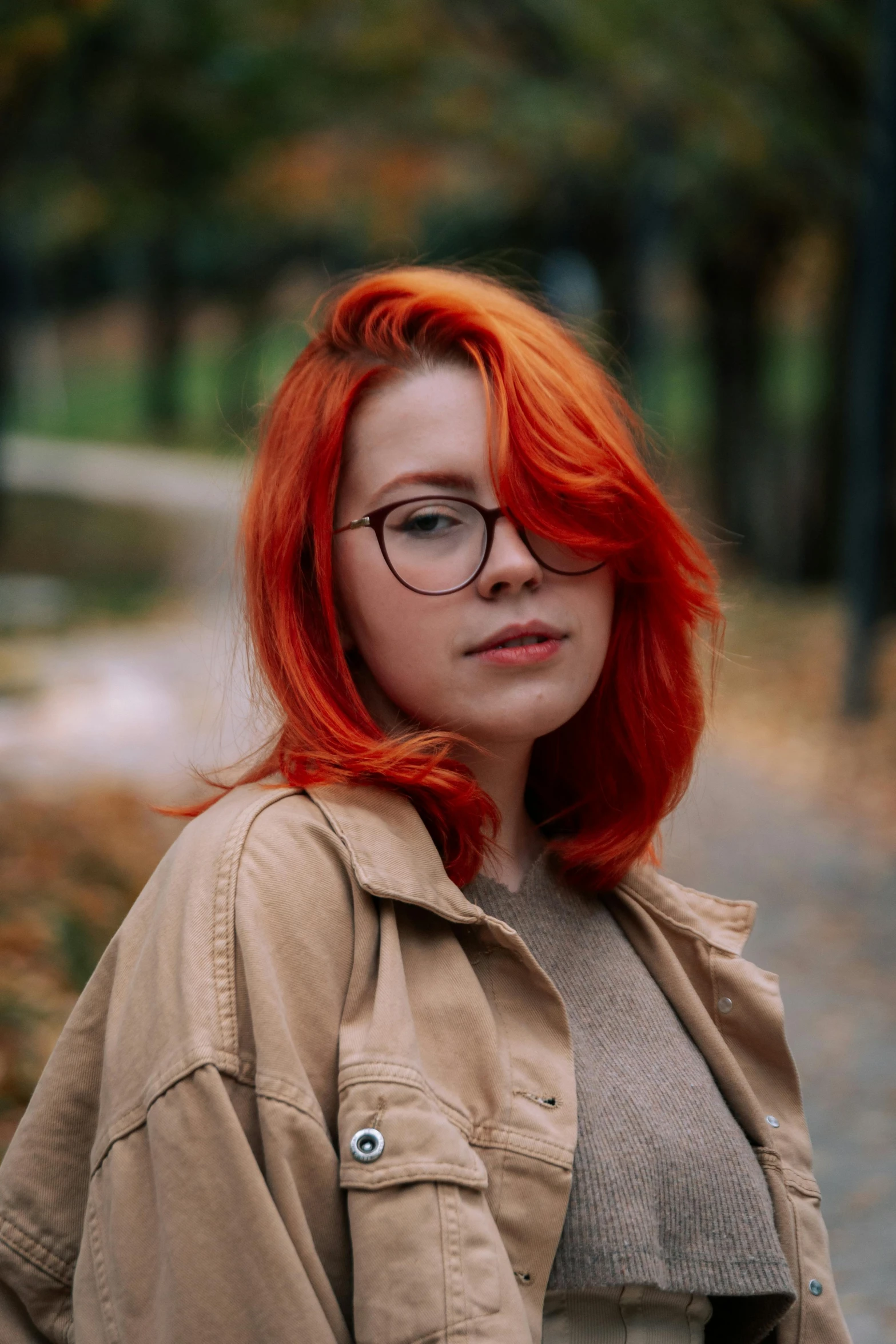 a woman with red hair and glasses in the park