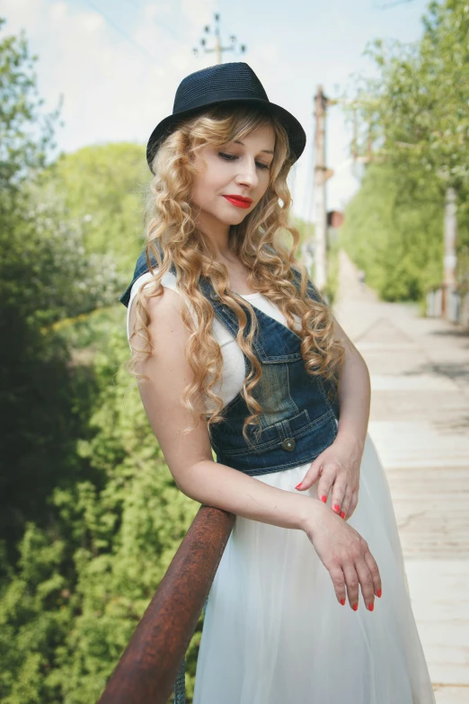 a lady standing on a wooden bridge next to trees