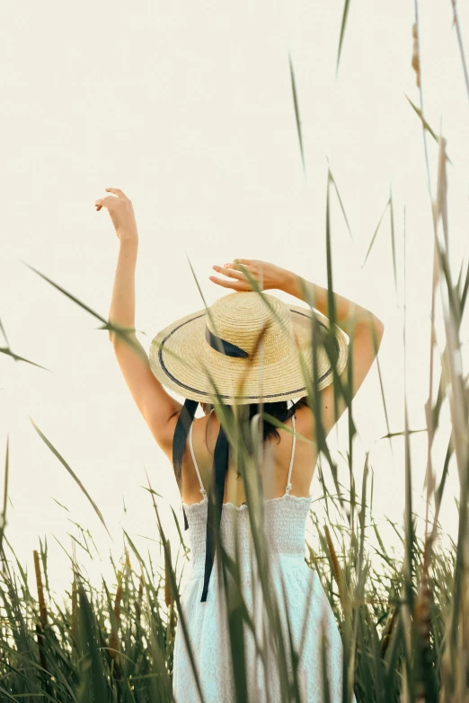 a woman is standing in a field with her arms raised