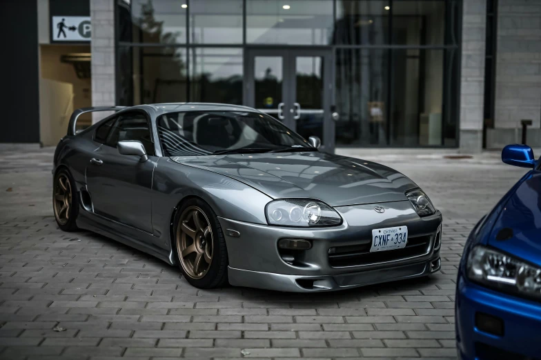 two silver sports cars parked in front of an office building