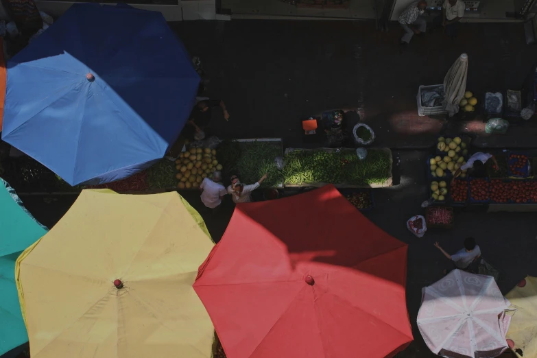 an overhead view of several people holding colorful umbrellas