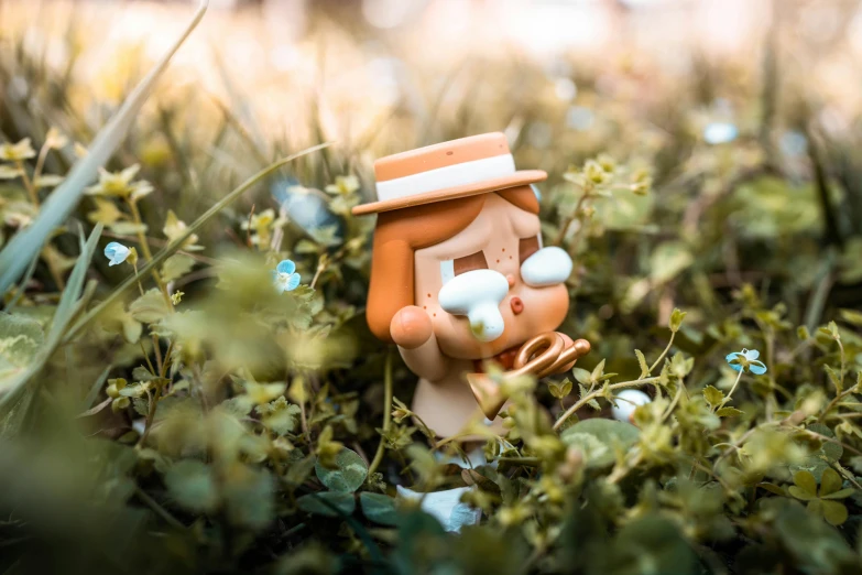 small toy figure with white pearls, in green plants