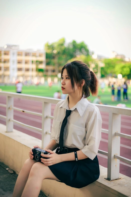 woman in dress sitting on rail next to grass and building