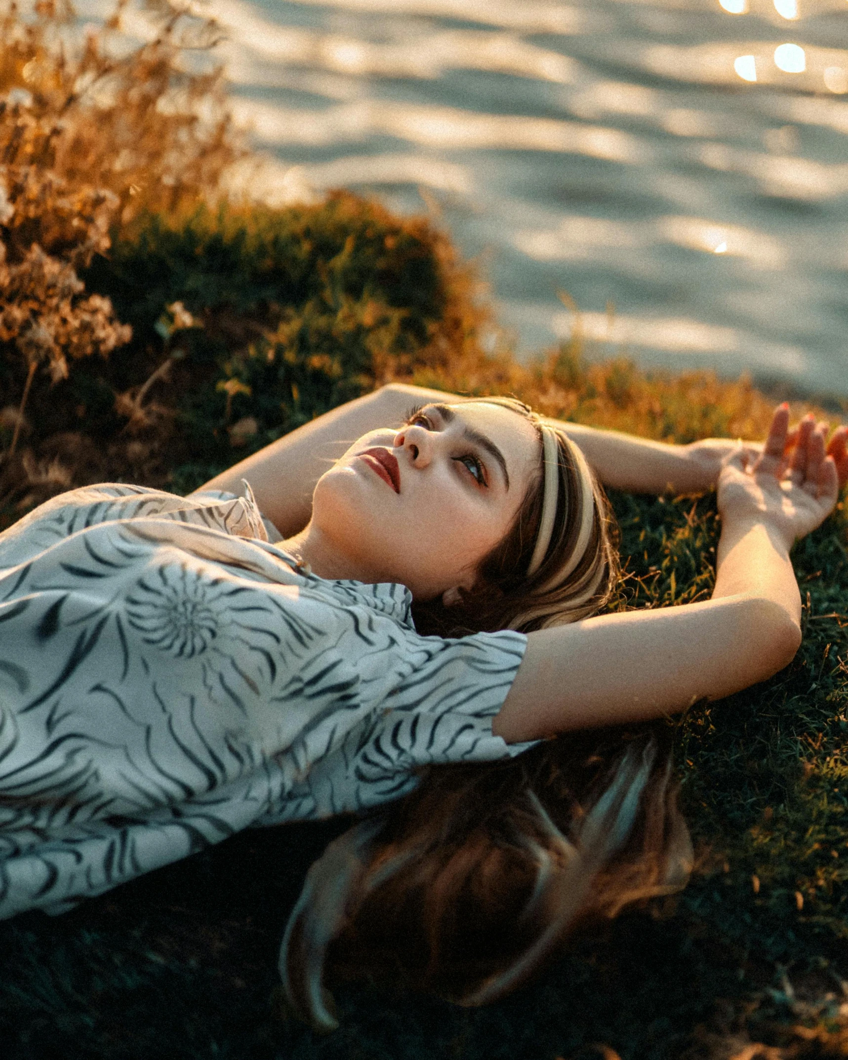 a woman laying on the ground in front of water