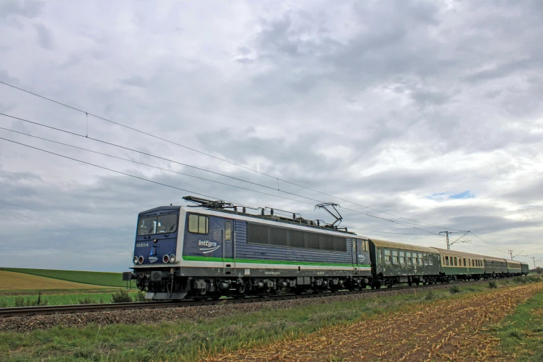 a blue train traveling past a lush green field