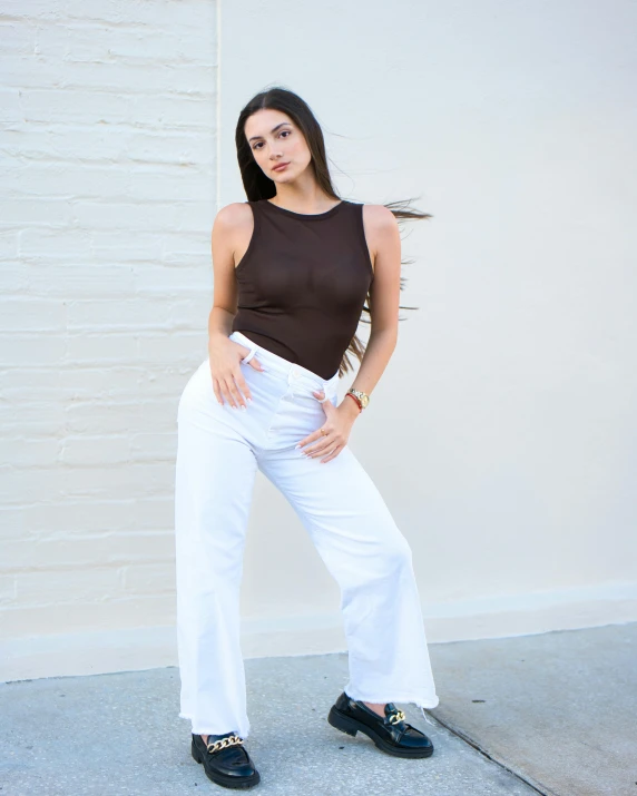 a woman posing in front of a white wall