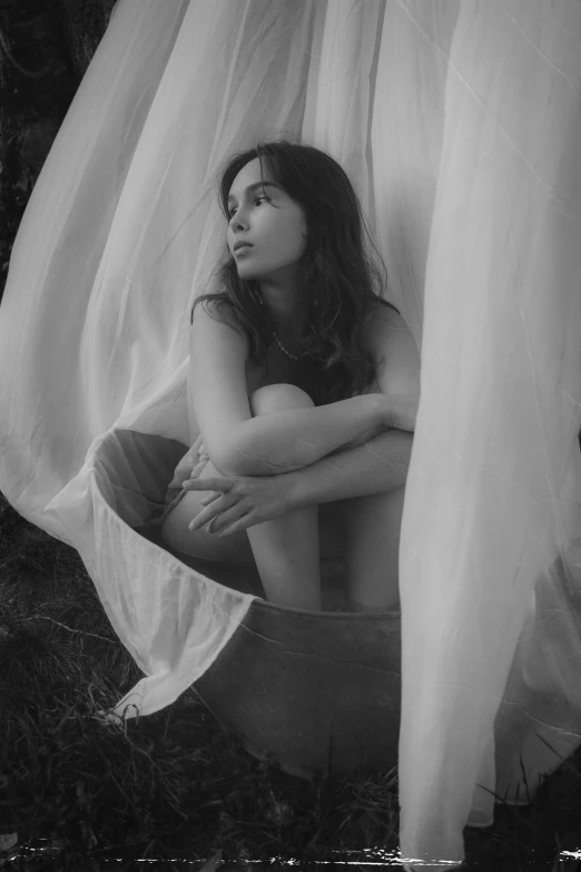 a woman sitting on top of a bucket in a forest