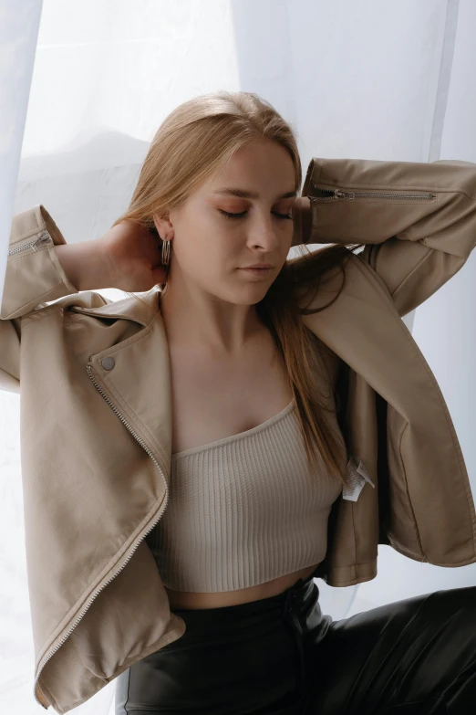 young woman wearing a beige top and a leather jacket with ruffle sleeves