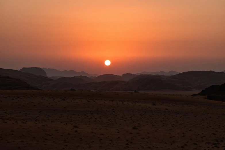 a sunrise is seen over an arid area