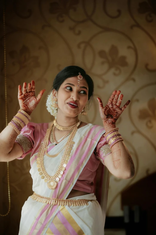 a woman in a pink and white blouse with two hands on her face