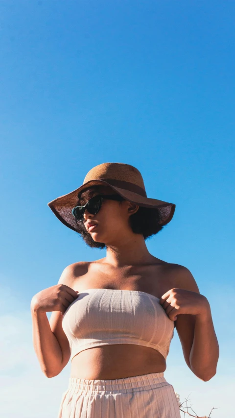 a woman wearing a large hat standing in front of a blue sky