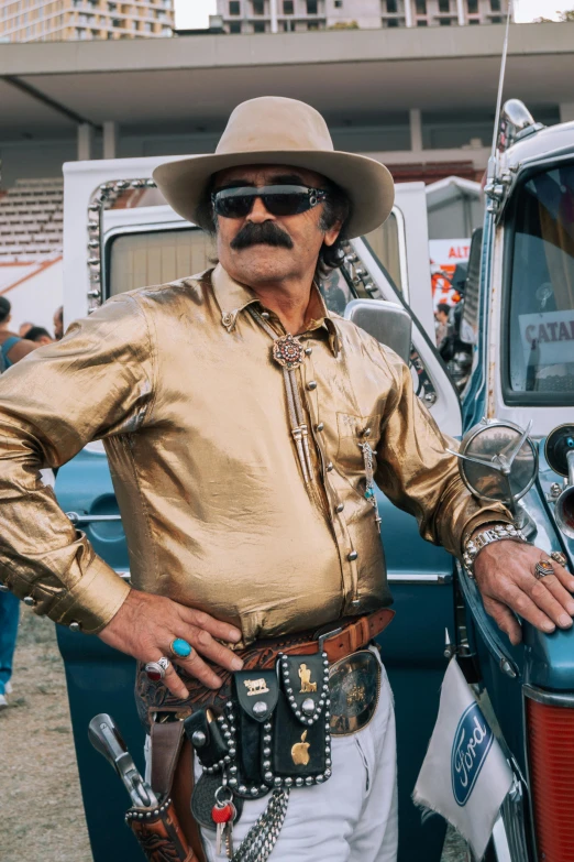 a man is dressed up as a cowboy leaning on his old truck