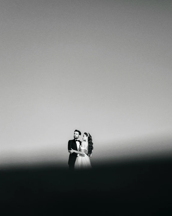 a bride and groom stand against the light in black and white