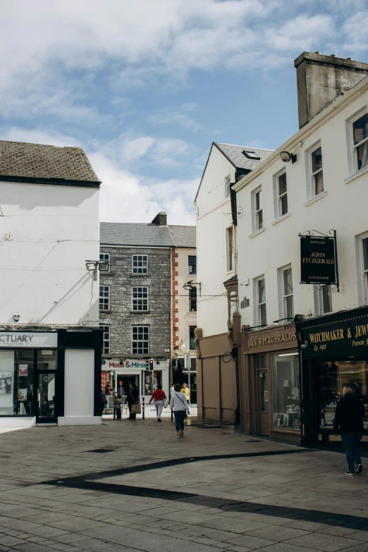 pedestrians are walking on the paved pavement by some shops