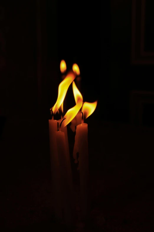 four lit candles on a table in the dark