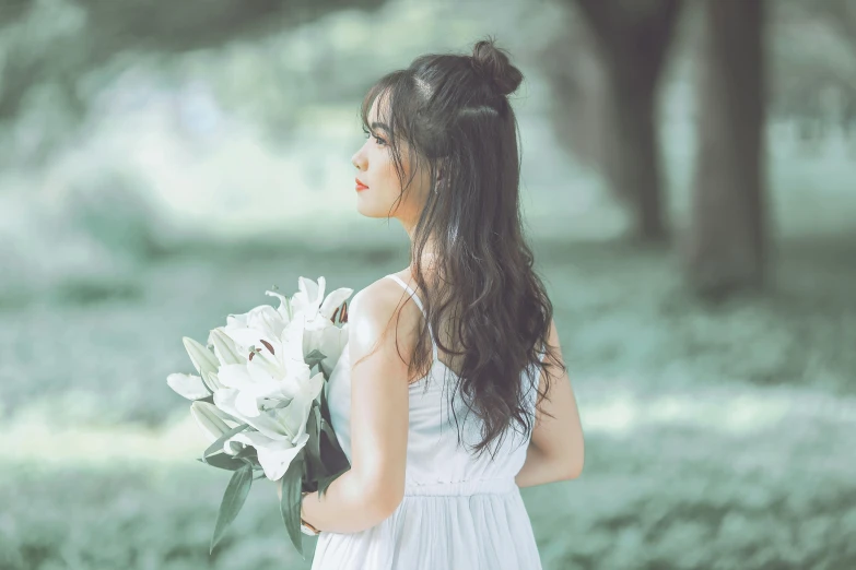 woman in white dress holding white flowers on field