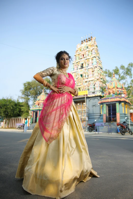 a woman in an ethnic fashion poses in front of an indian temple