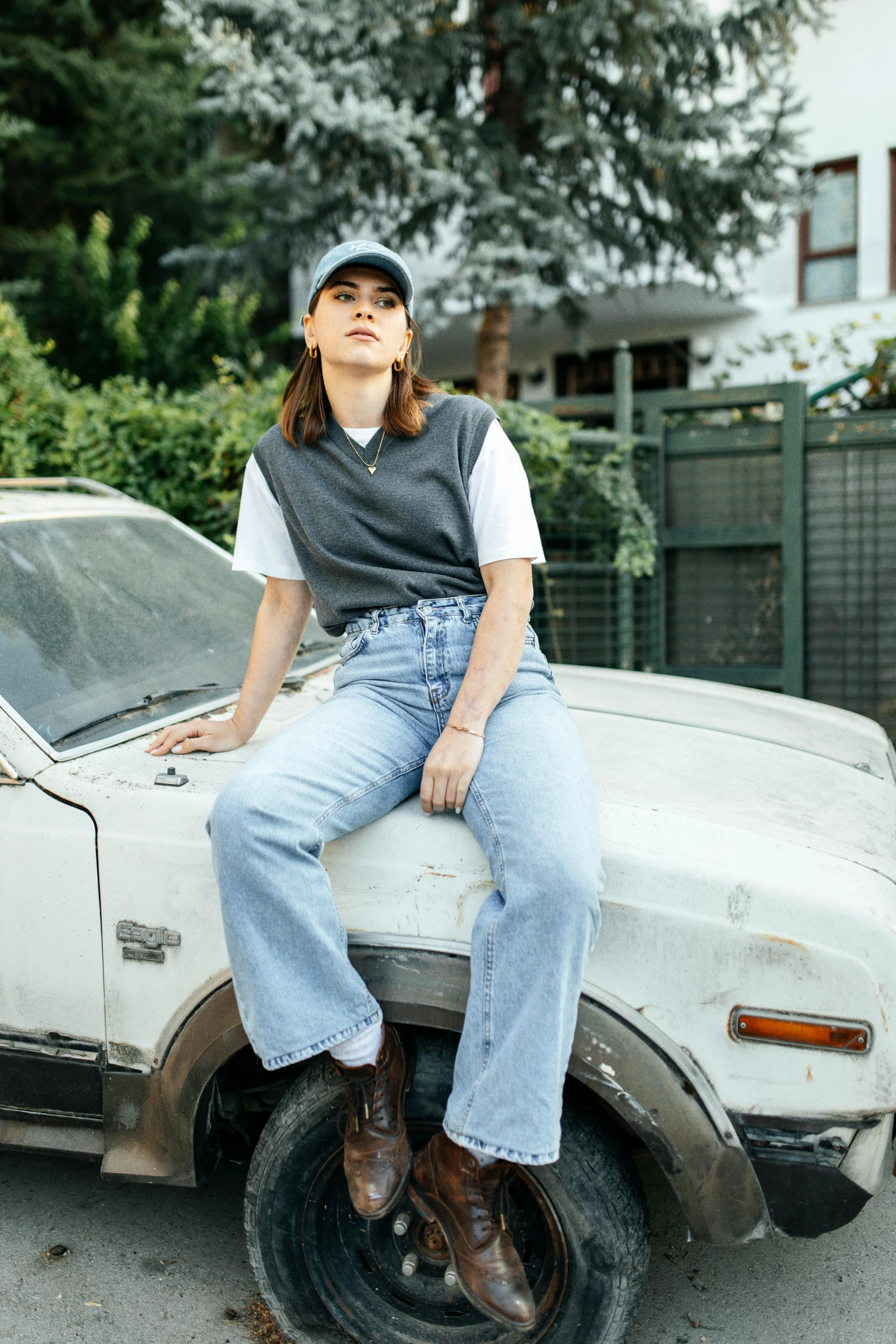 a woman sits on top of a car in a parking lot