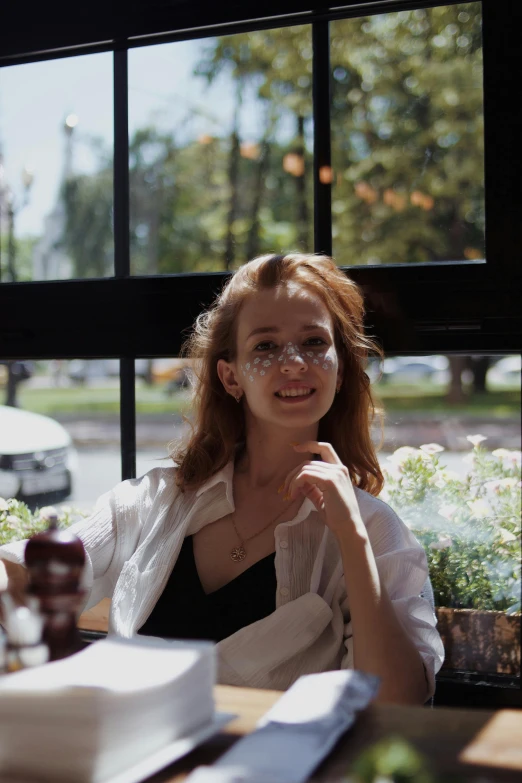 a woman wearing glasses sits in front of the window