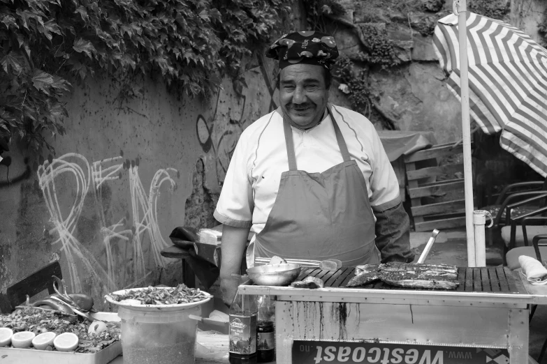 a man wearing an apron behind a food stand