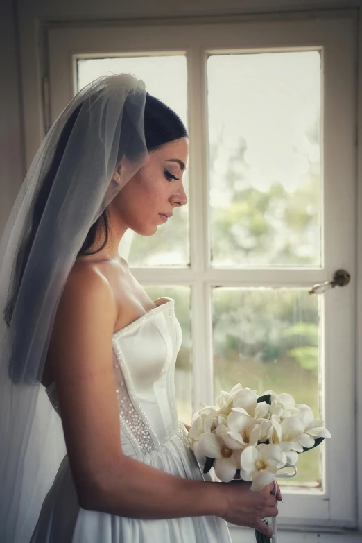 the bride poses for a pograph near an open window