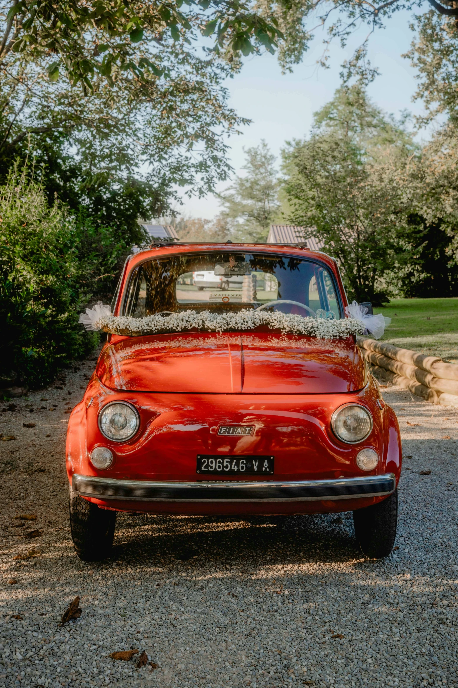 a red car parked next to a tree on a road