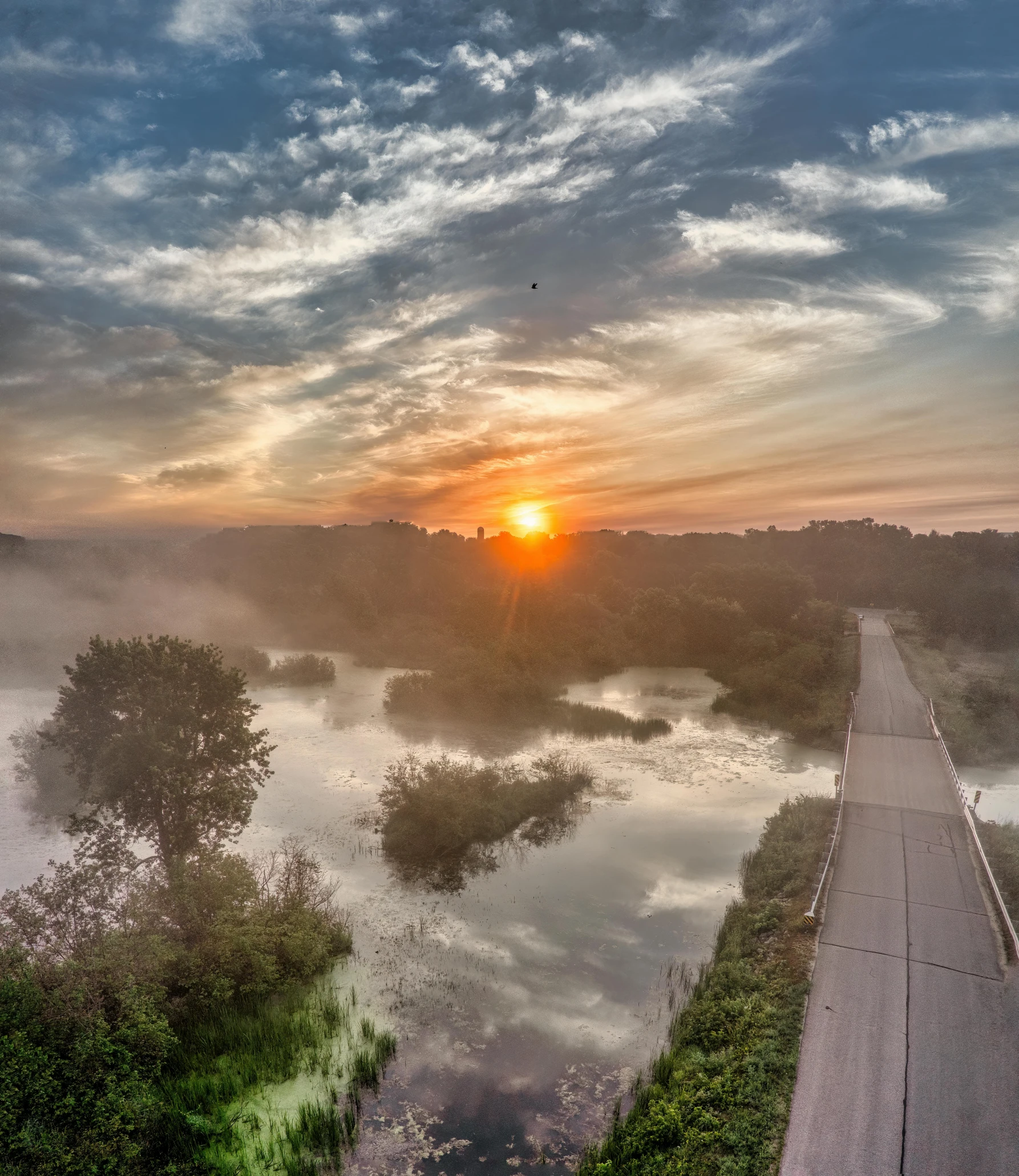 a beautiful sunrise on the river with a small town next to it