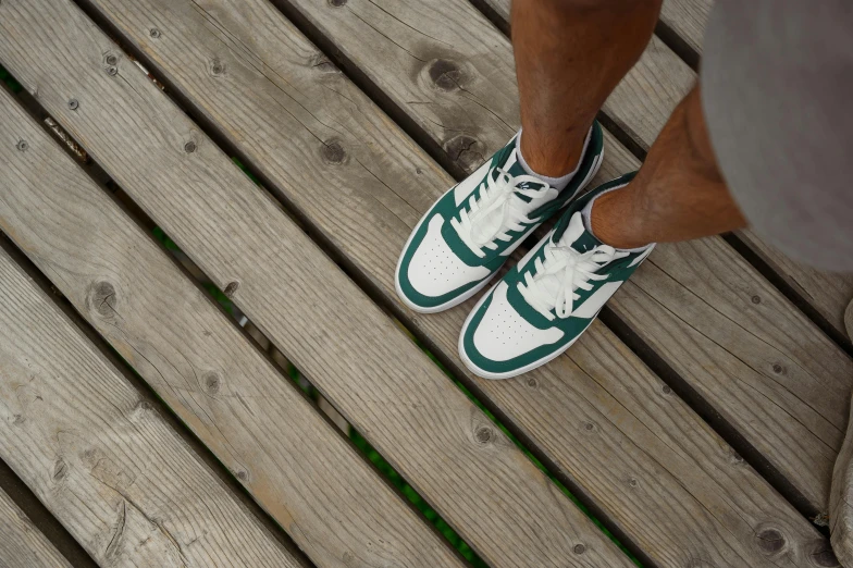 a man standing on a deck next to his white sneakers