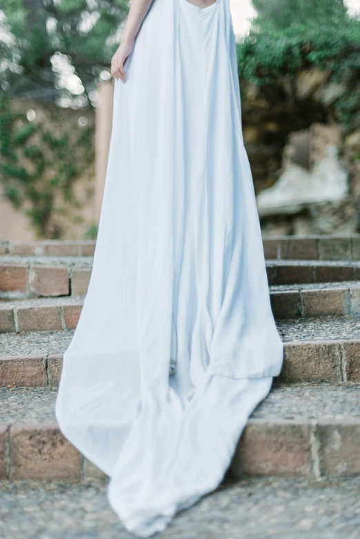 a woman standing on stairs, dressed in white