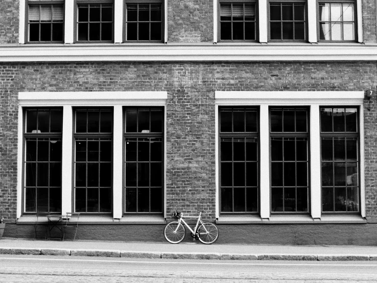 black and white image of a bicycle leaned against the side of a building