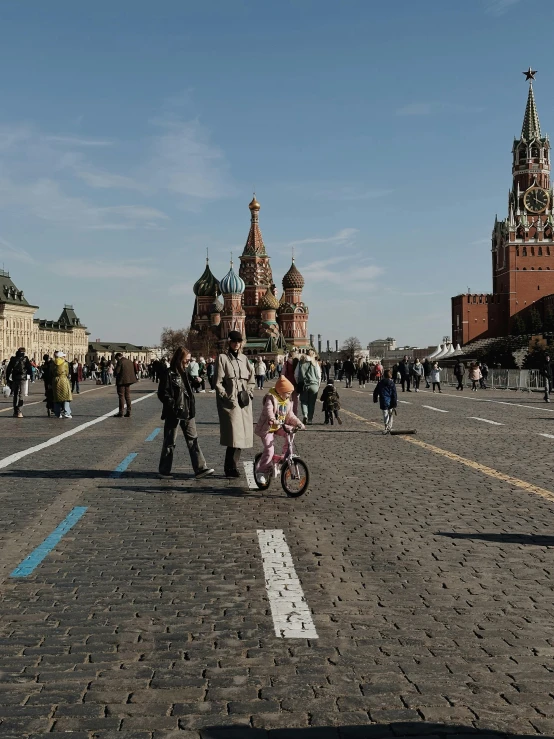 a woman and child are walking in a street between two large buildings