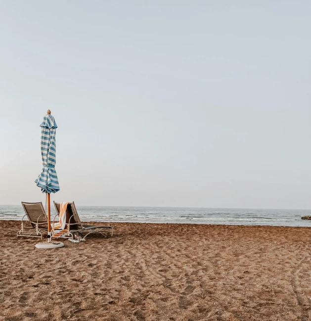 a row of beach chairs and an umbrella are on the beach