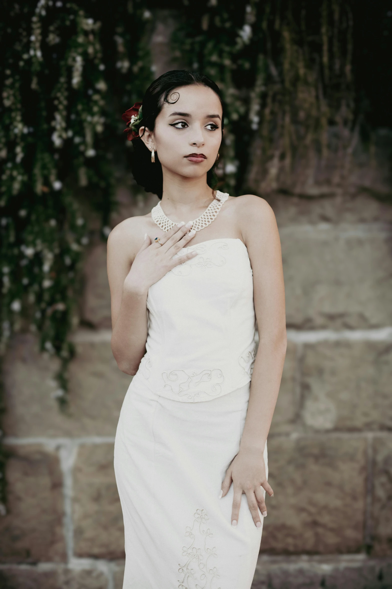 an attractive bride with flowers on her head in front of a stone wall