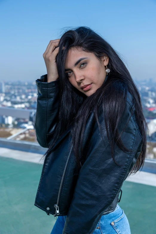 woman with long hair looking back, while standing in front of a city