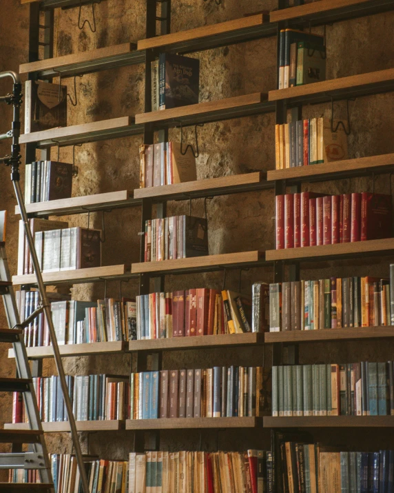 a long book case filled with lots of books next to stairs