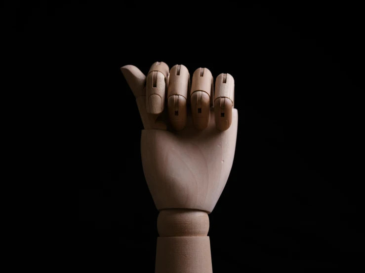this is a wooden hand holding three finger dolls