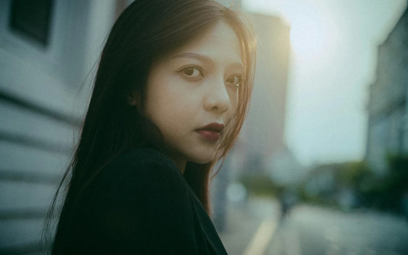 a close - up of a young female standing next to buildings