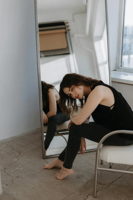 a woman sitting on a chair in front of a mirror