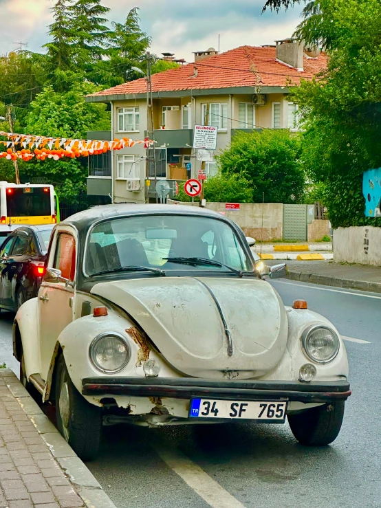 an old beetle car in front of another car driving on the street