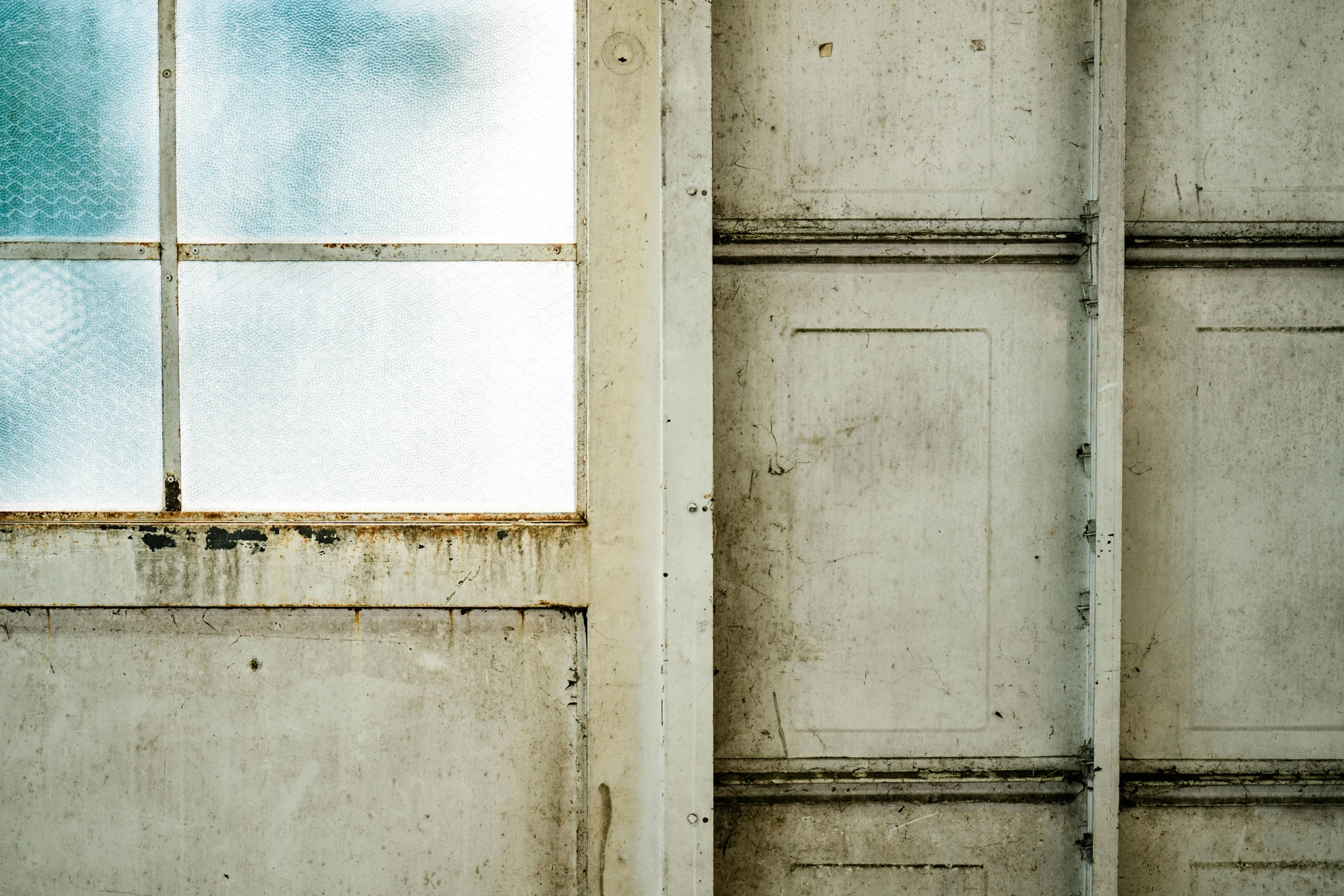 a broken window with a sky view from a dirty concrete wall