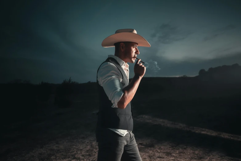 man in cowboy hat smoking a cigarette with dark background