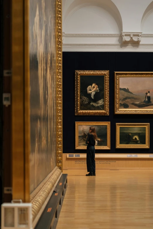 an art museum with two people looking at paintings on the wall