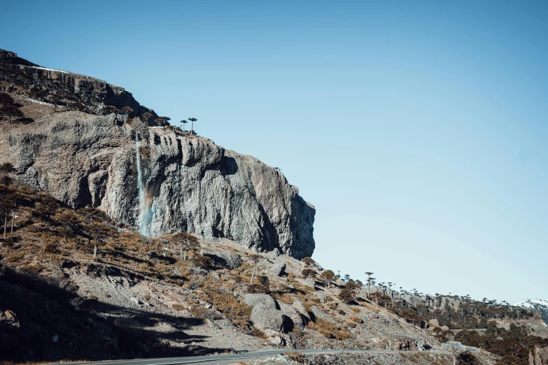 the side of a mountain that has a road in front of it