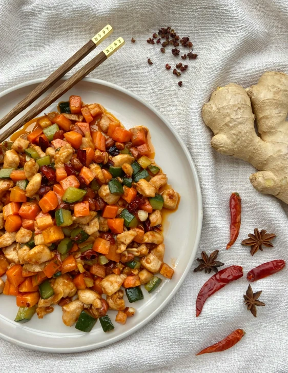 a plate full of sliced vegetables and ginger sticks on a cloth