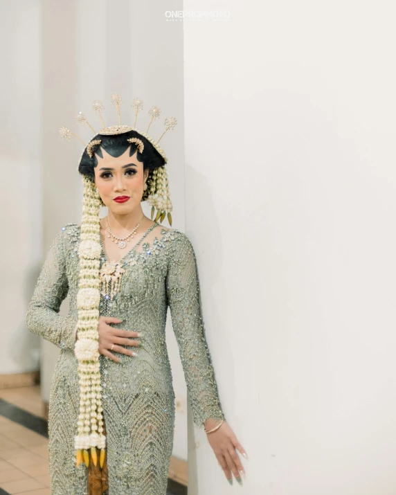 woman with dress holding her hair tied back and a headpiece hanging from her arm